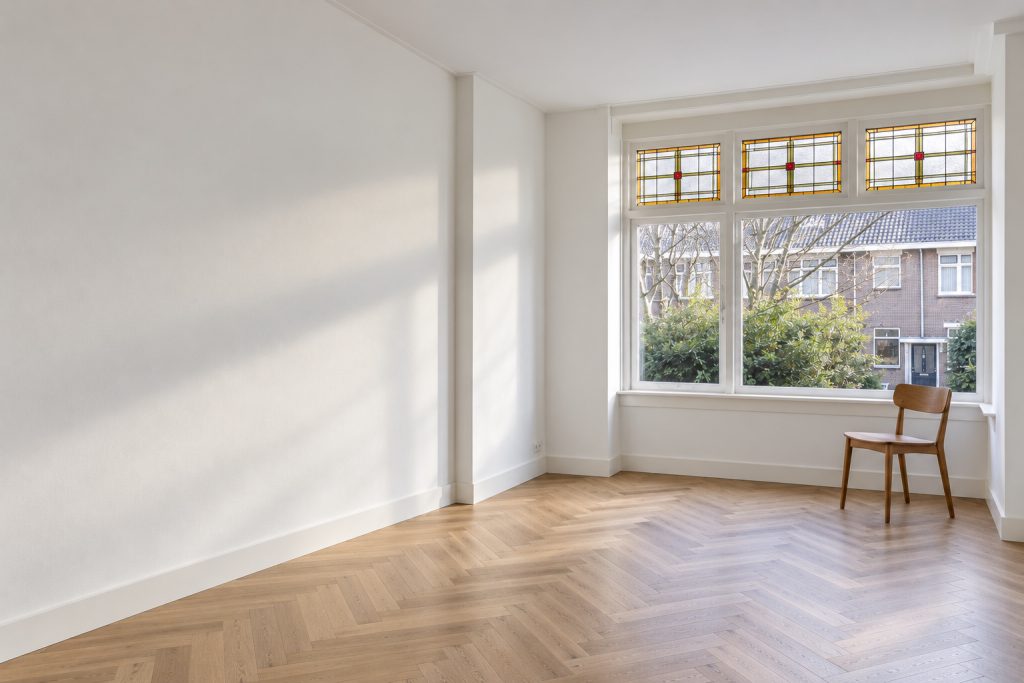 Woonkamer na oplevering, gesausd, met licht door de erker
